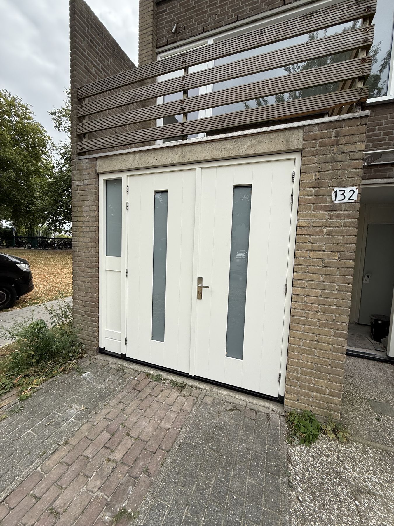 Nieuwe crèmekleurige dubbele deuren met glasstroken in een bakstenen gevel