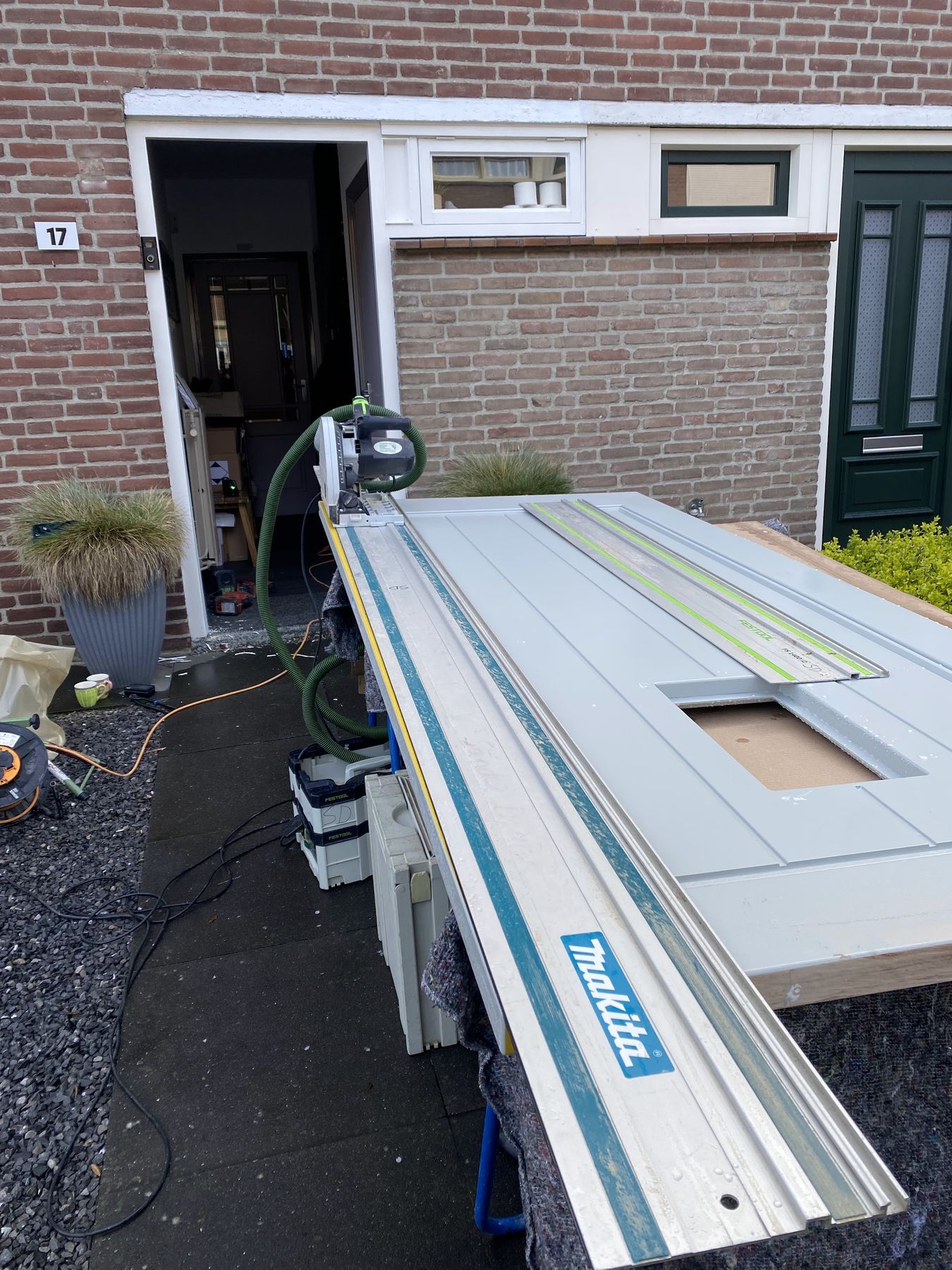 Deur op schragen die met een invalzaag op maat wordt gezaagd voor een voordeur